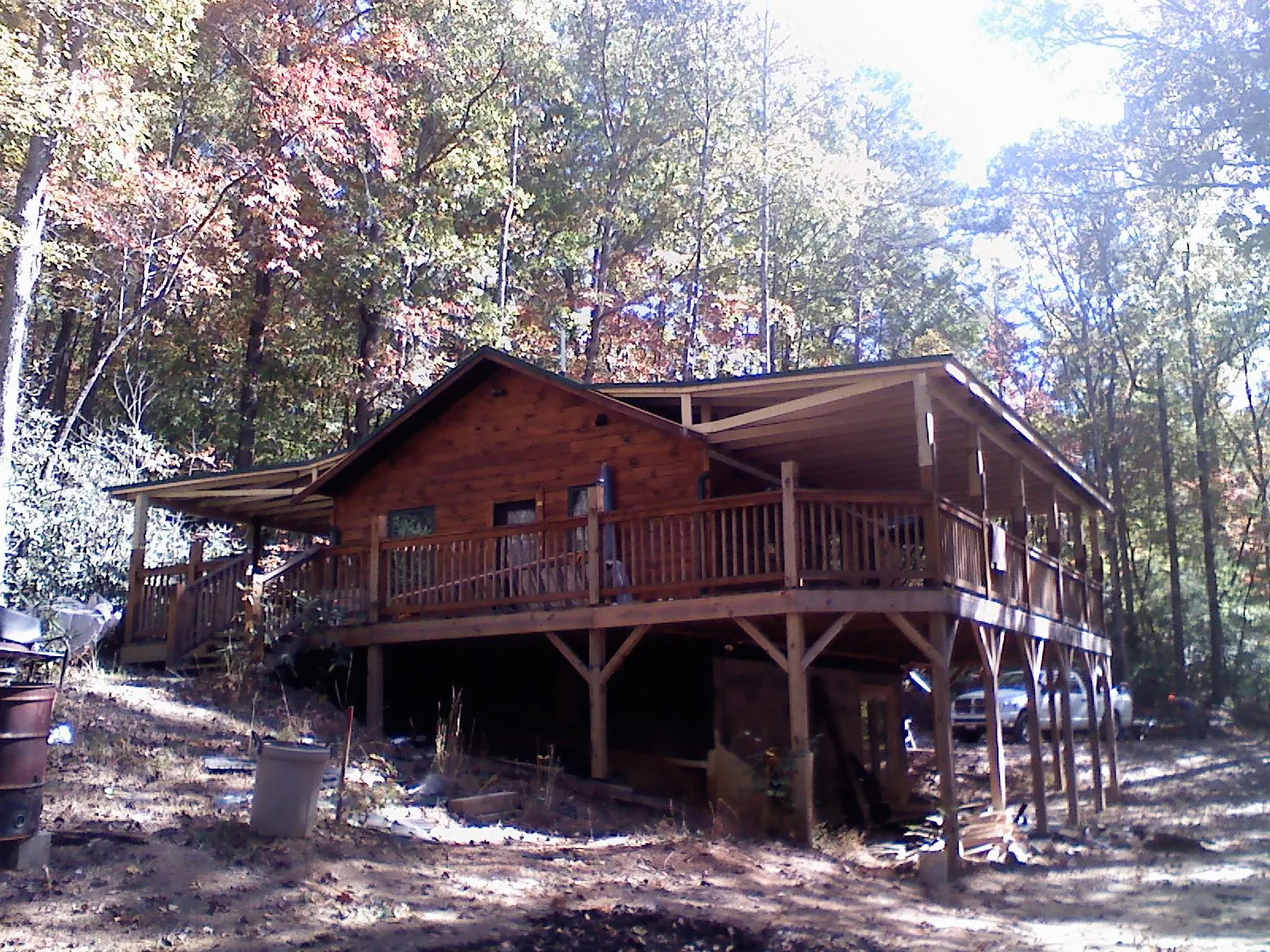 Log cabin with a wraparound porch and metal roof in the fall in Alexandria
