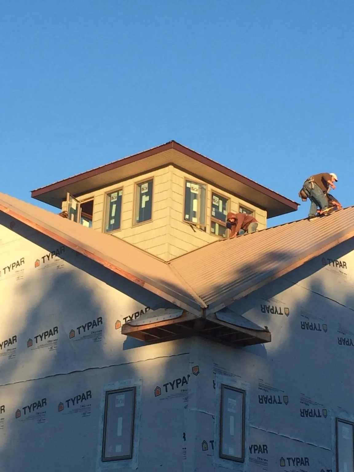 Roofers working around a rooftop cupola on a new metal roof at sunset — Roof Waterproofing in Alexandria by Roofing Brothers